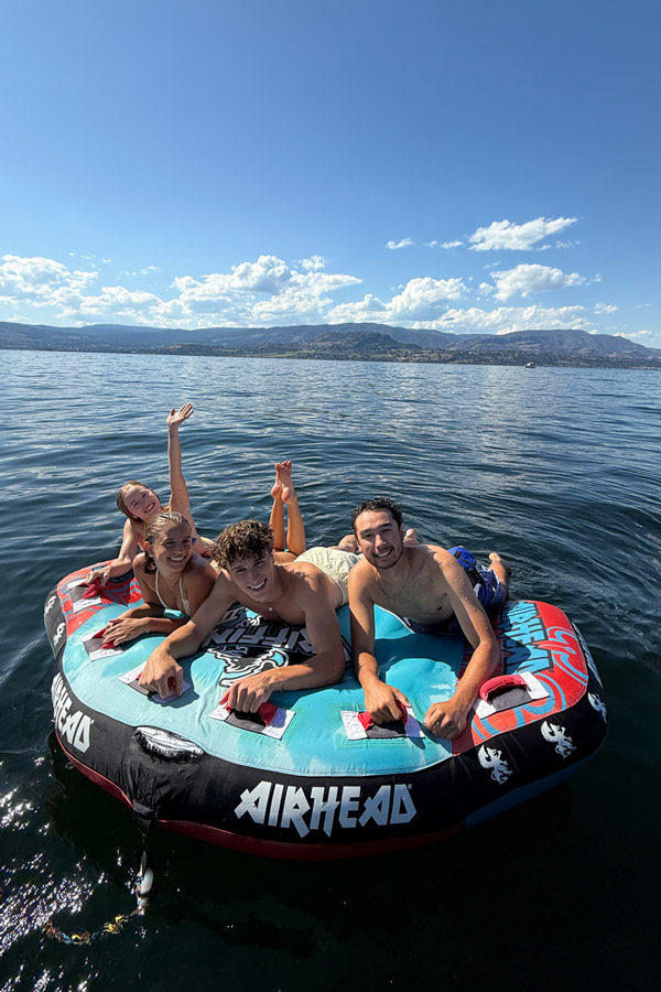 Four people riding a towable tube on Okanagan Lake
